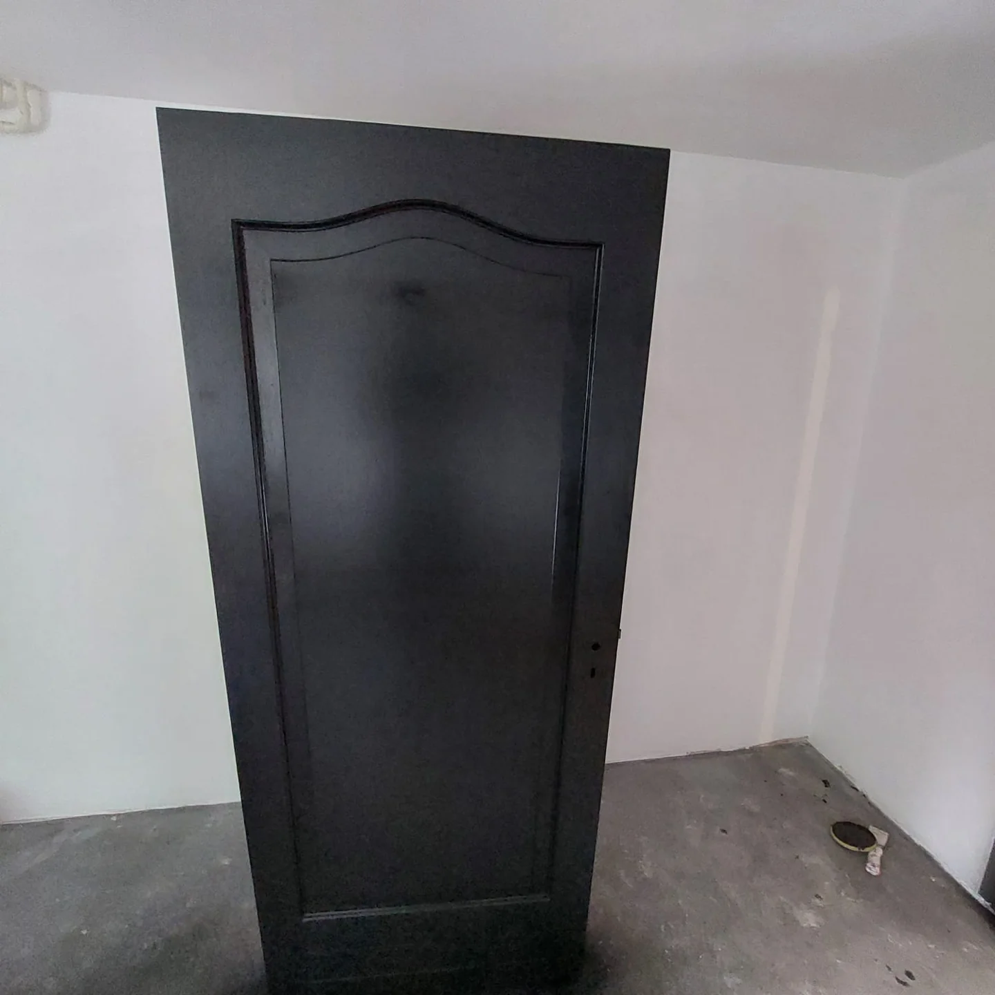 Donkere deur tegen witte wand, onaffe vloer
