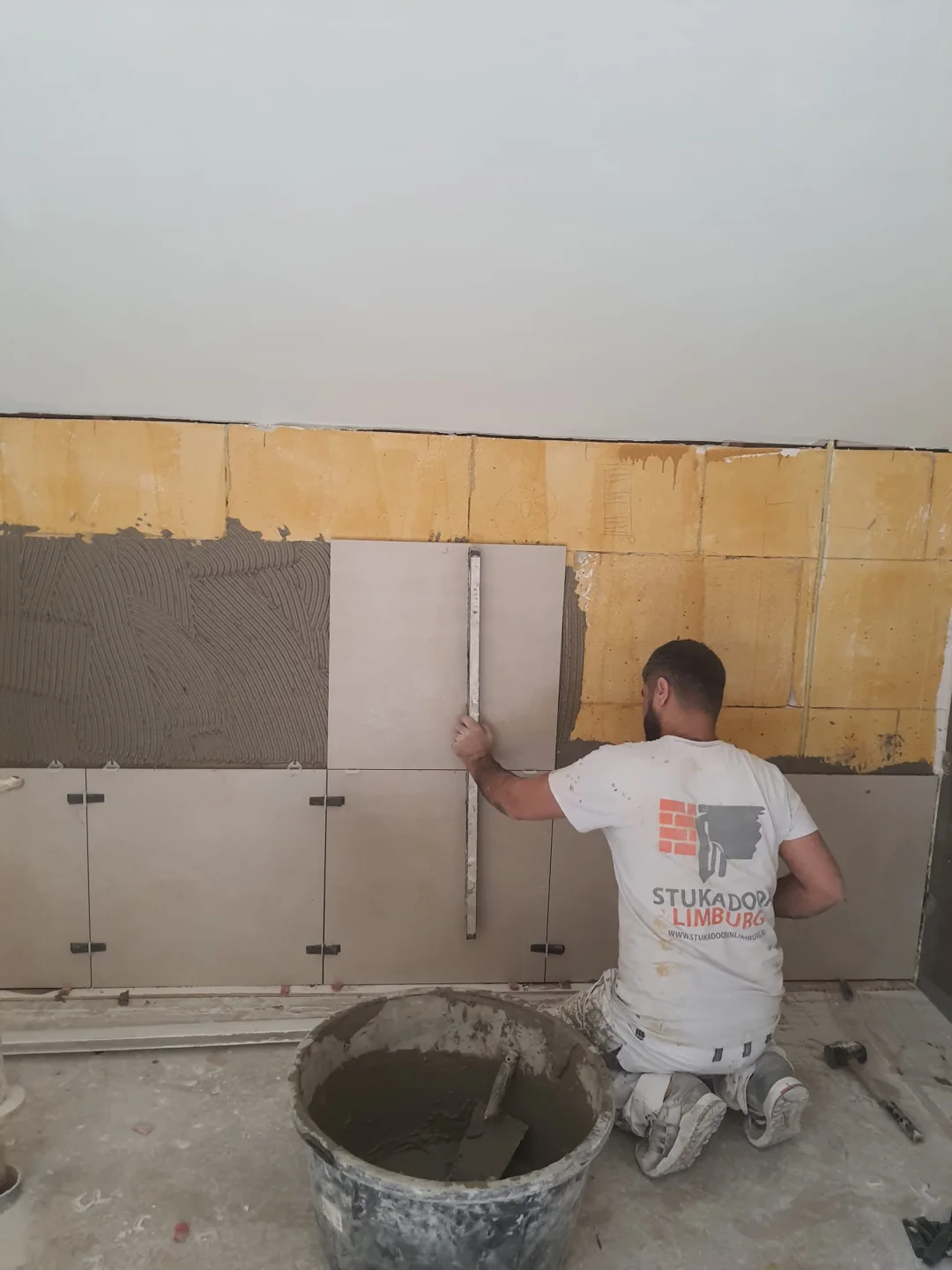 Medewerker bij wandtegelplaatsing met gereedschap